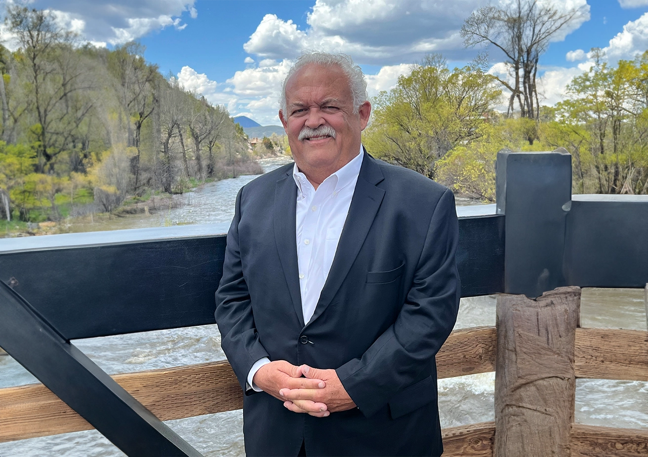 A man in a suit standing on top of a wooden deck.